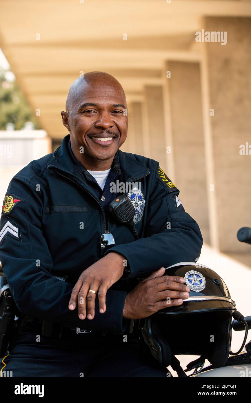 Portrait de l'officier de police assis sur sa moto à l'extérieur en regardant vers la caméra souriante Banque D'Images