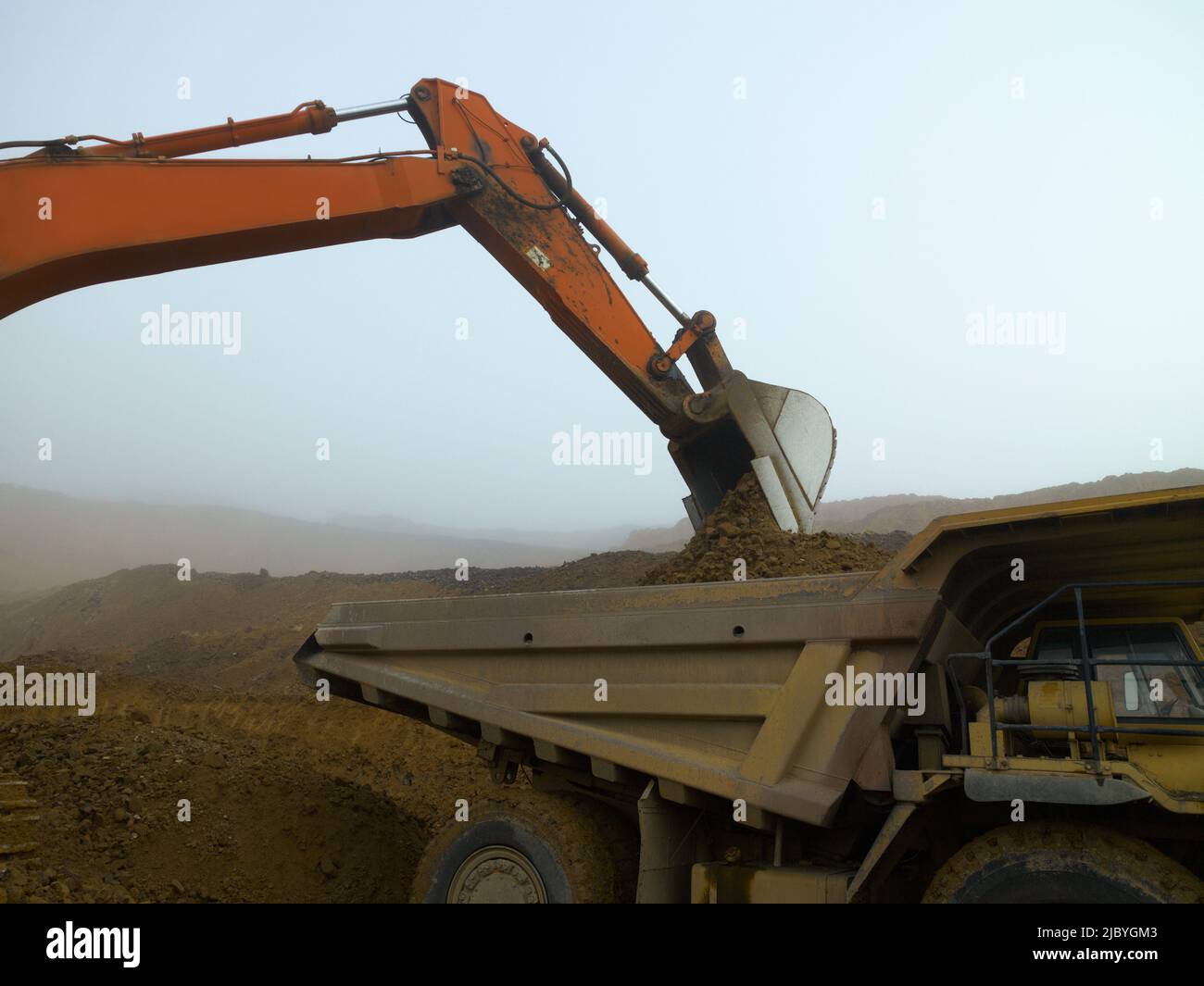 Grand camion de chargement de creuseur dans une carrière brumeuse Banque D'Images