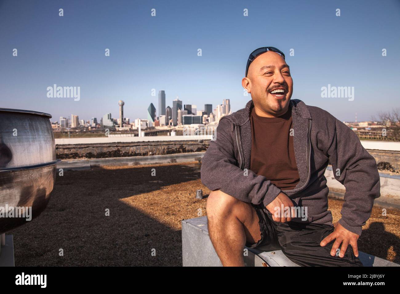 Laughing Man sitting on rooftop Banque D'Images