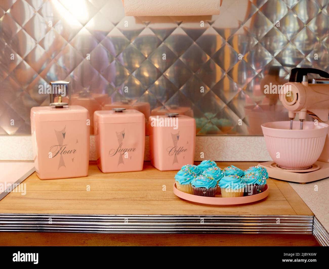 Cuisine du milieu du siècle avec des électroménagers roses et des petits gâteaux bleus. Banque D'Images