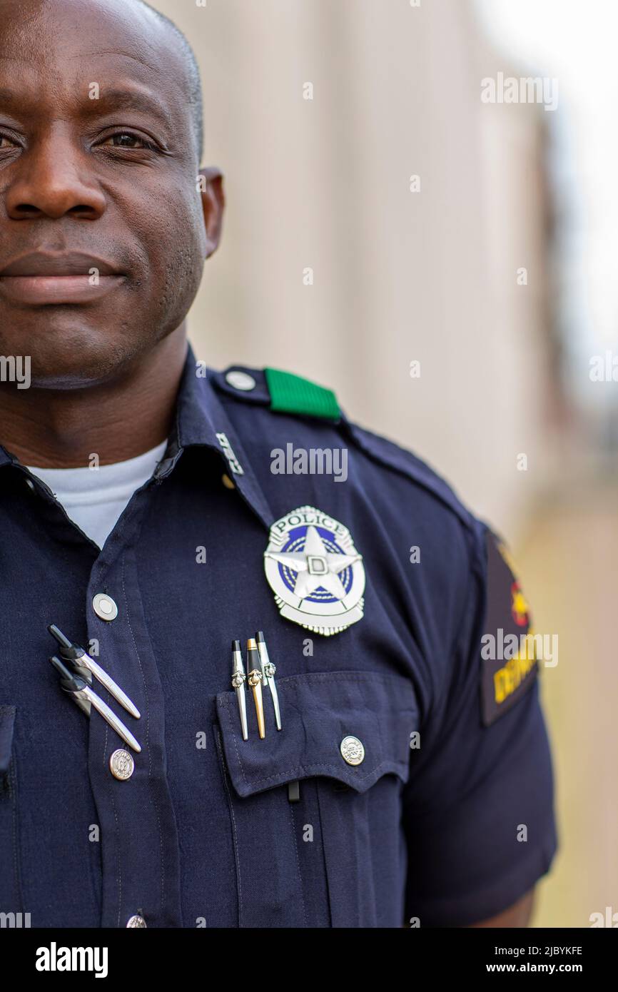 Portrait de l'officier de police debout dans la rue devant la voiture de l'escouade regardant vers la caméra avec les bras derrière son dos Banque D'Images