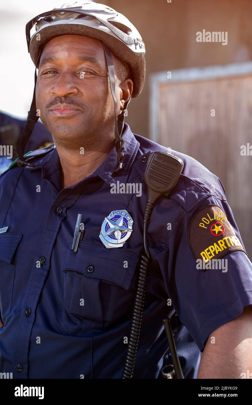 Portrait de l'officier de police de vélo debout à l'extérieur en regardant vers la caméra sourire Banque D'Images