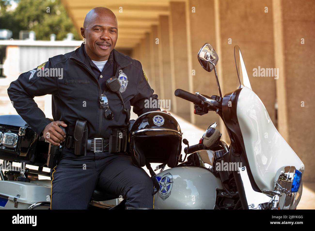 Portrait de l'officier de police assis sur sa moto à l'extérieur en regardant vers la caméra souriante Banque D'Images