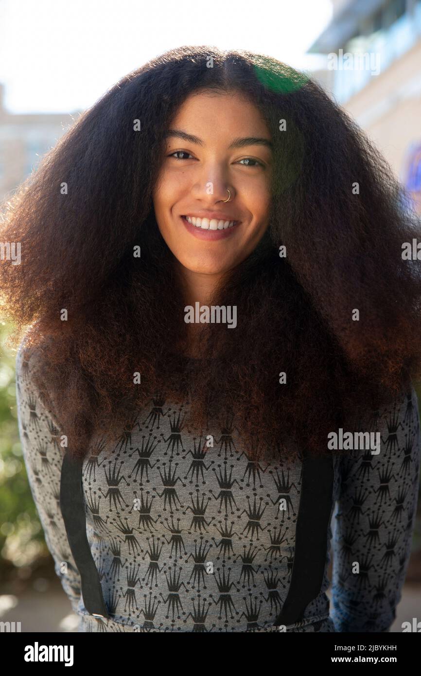 Portrait d'une femme avec de longs cheveux debout à l'extérieur, regardant l'appareil photo Banque D'Images