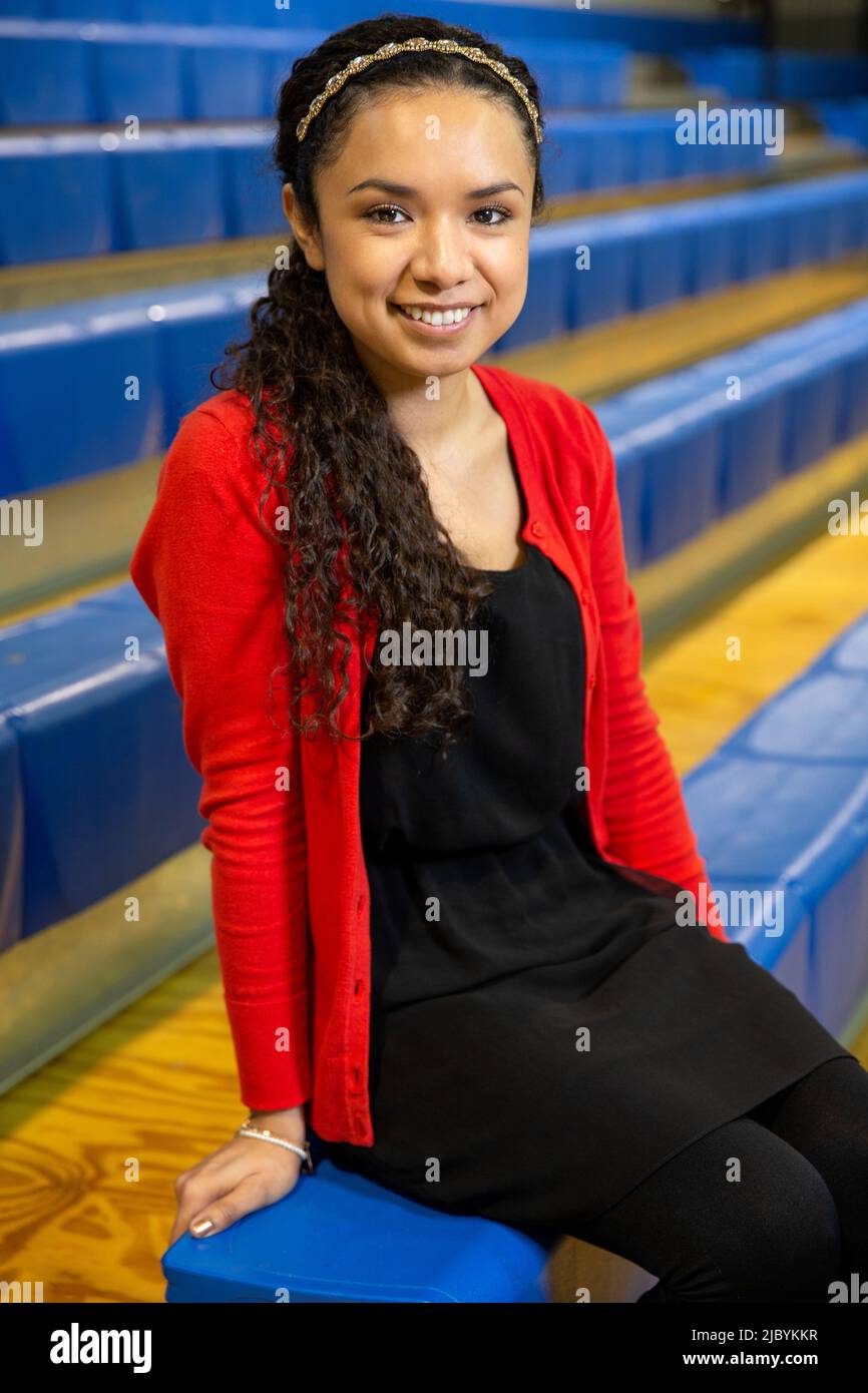 Portrait souriant d'une jeune femme ethnique assise sur des gradins dans un gymnase Banque D'Images