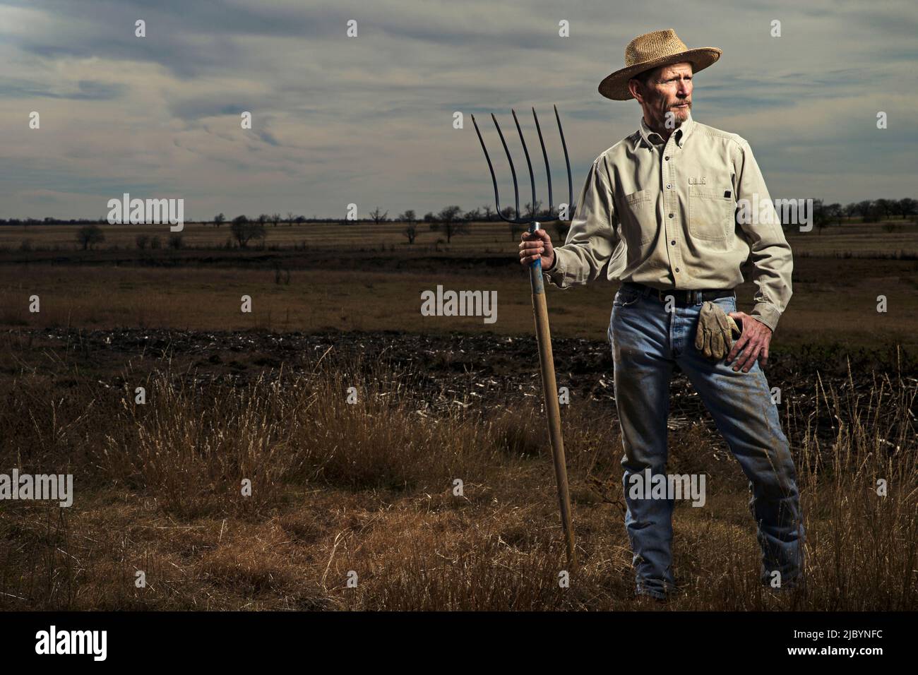 Farmer standing et fourche dans le champ Banque D'Images