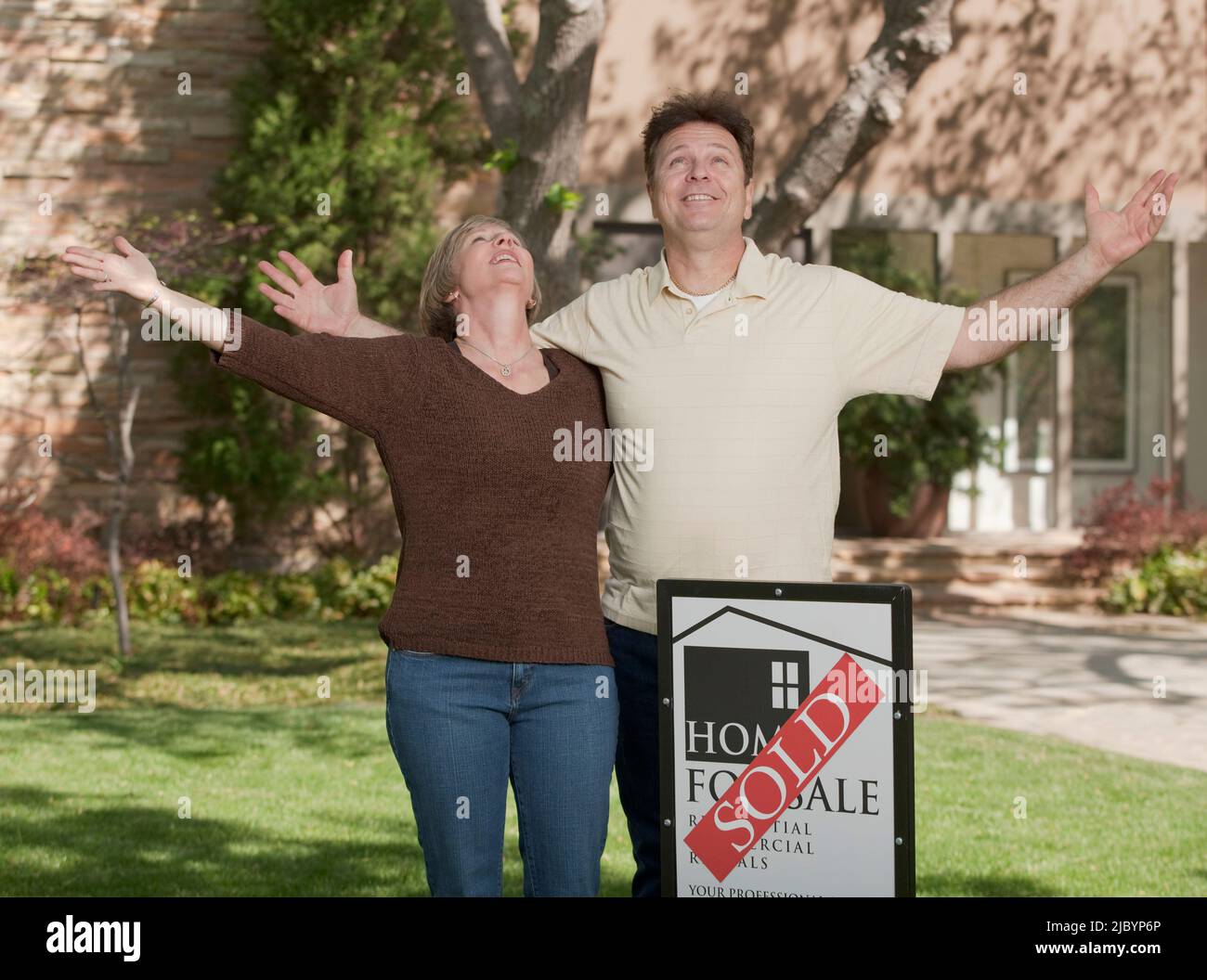 Couple standing in yard with sold sign Banque D'Images
