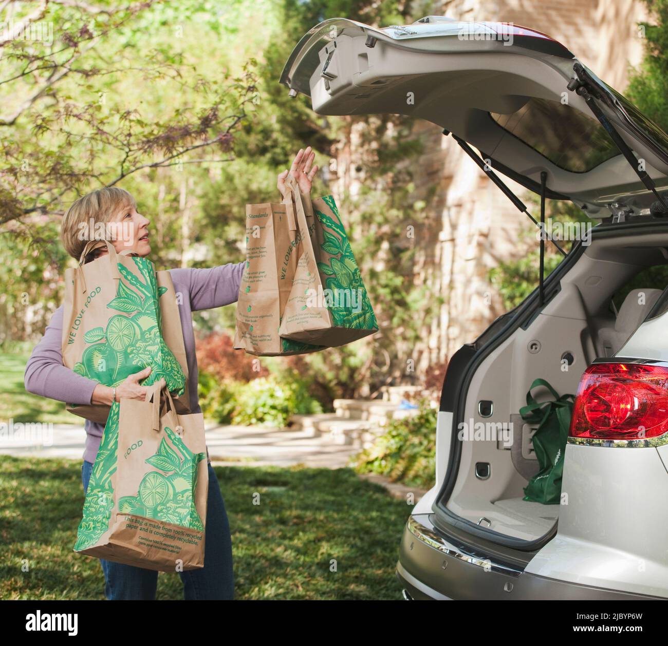 Femme prenant des sacs d'épicerie hors de la voiture Banque D'Images