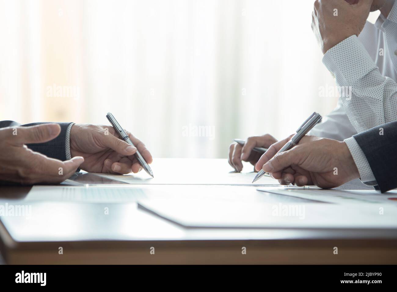 Dans une salle de réunion, un gros plan de trois hommes d'affaires ou analystes discute des performances de l'entreprise et des États financiers Banque D'Images