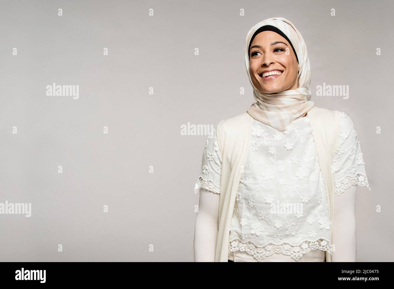 Portrait d'une femme de race mixte sur fond gris portant un hijab. Banque D'Images