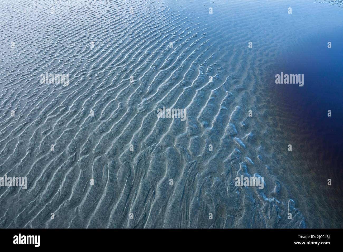 Des motifs de sable et un bassin d'eau avec des tanins à marée basse sur la plage Tonquin, près de Tofino, C.-B., Canada. Banque D'Images