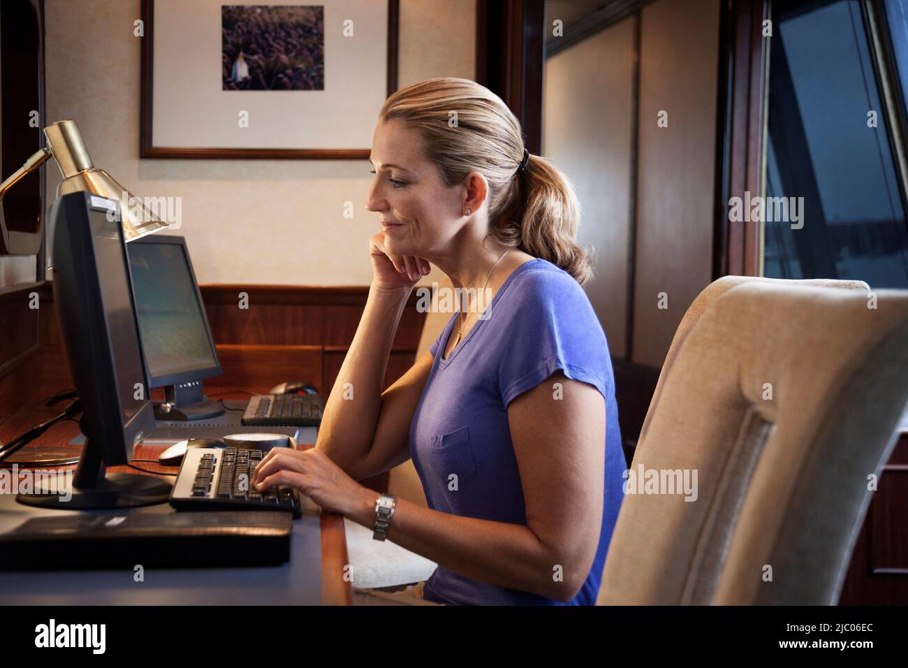 Femme utilisant un ordinateur de bureau au bureau sur un bateau de croisière Banque D'Images