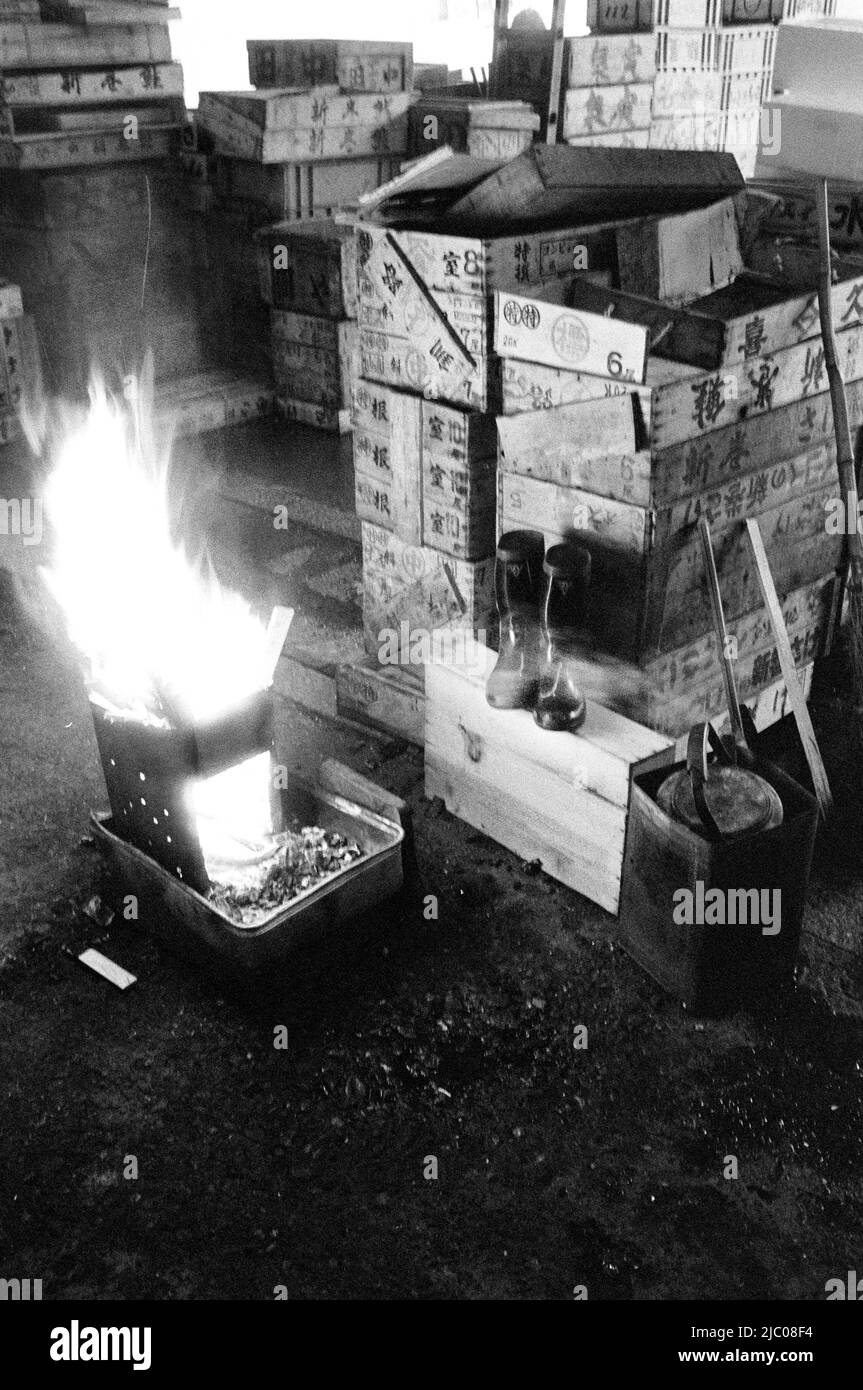 Japon, Tokyo, incendie au four à côté de la paire de bottes et de caisses d'expédition en bois à l'intérieur du marché du poisson Tsukiji Banque D'Images