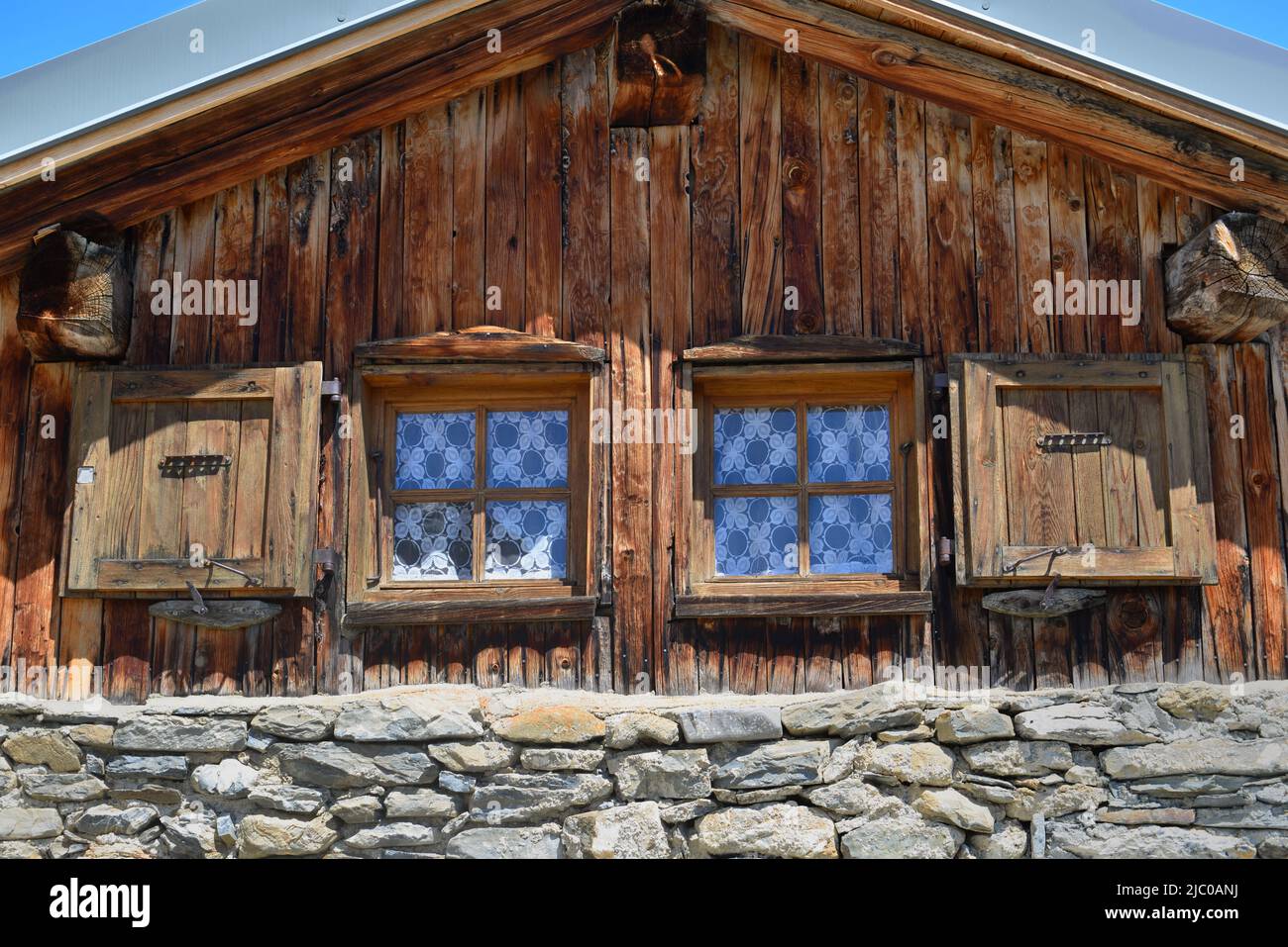 partie d'un chalet alpin traditionnel en bois avec deux petites fenêtres Banque D'Images