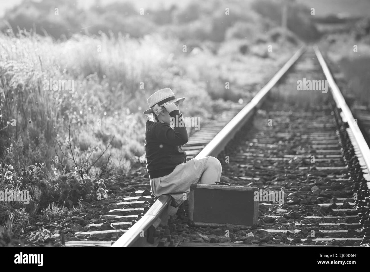 Photo rétro de petite fille avec de vieux bagages aux chemins de fer Banque D'Images