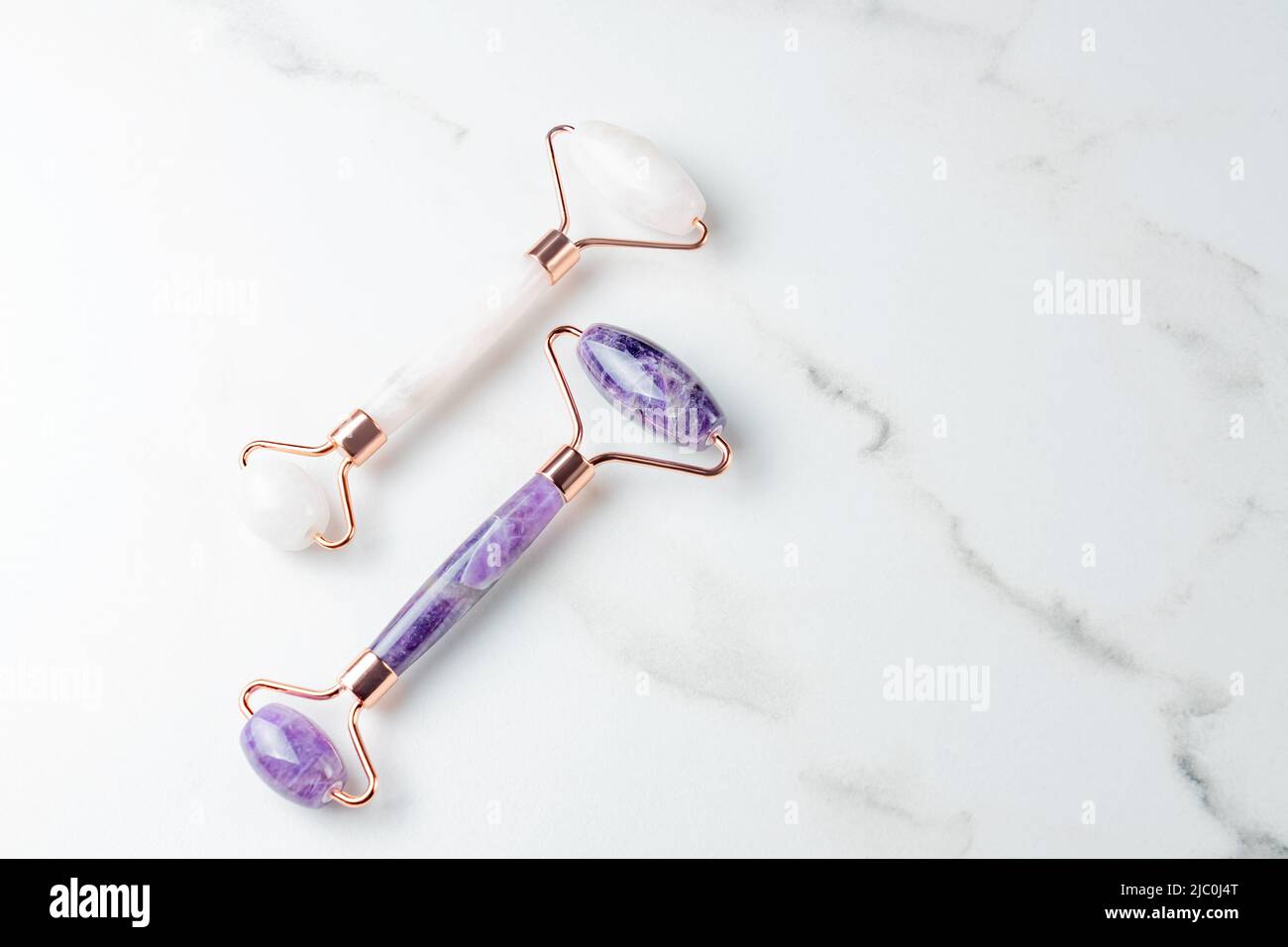 gros plan sur les rouleaux amethyst et rose quartz. Rouleaux de différentes couleurs pour le massage du visage. Vue de dessus, espace pour le texte. Concept de soins de beauté pour le visage. Cadre, Banque D'Images