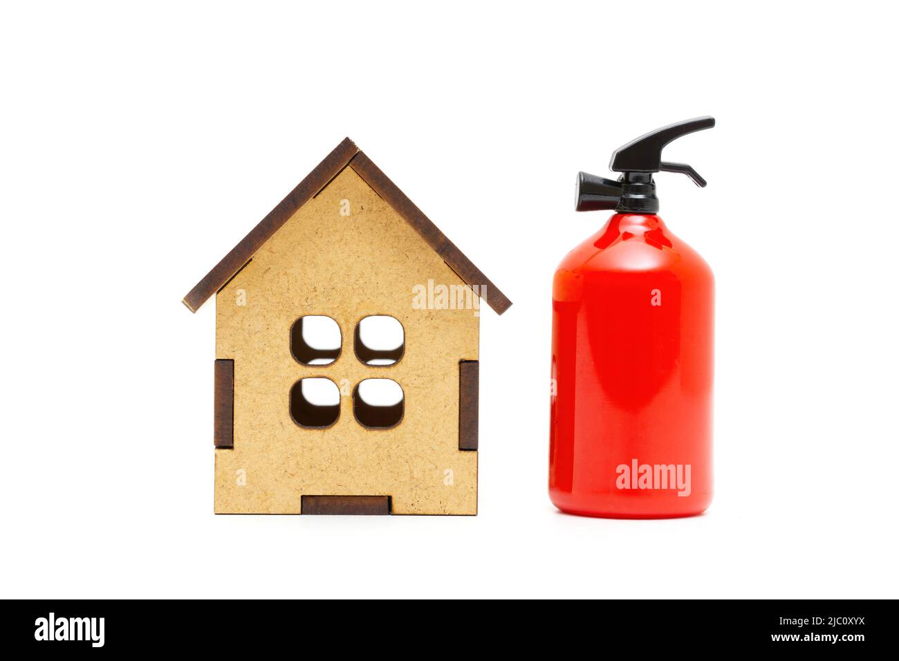 Extincteur de jouet placé par une maison miniature en bois isolée sur fond blanc. Appartement et condominium sécurité incendie. Banque D'Images