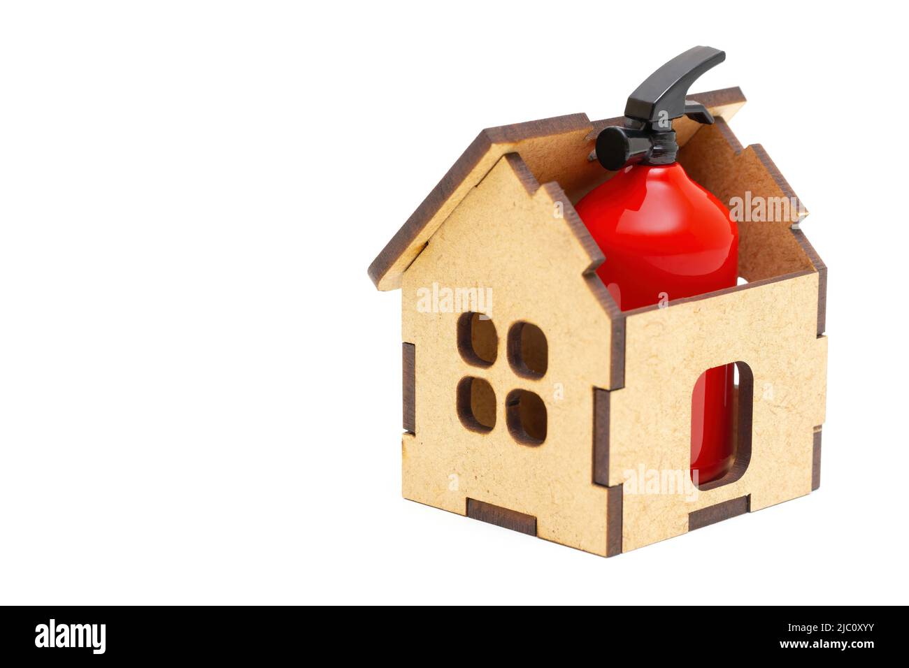 Petit extincteur rouge placé à l'intérieur d'une maison en bois de jouet isolée sur fond blanc. Mesures de prévention et de sécurité incendie à domicile. Banque D'Images