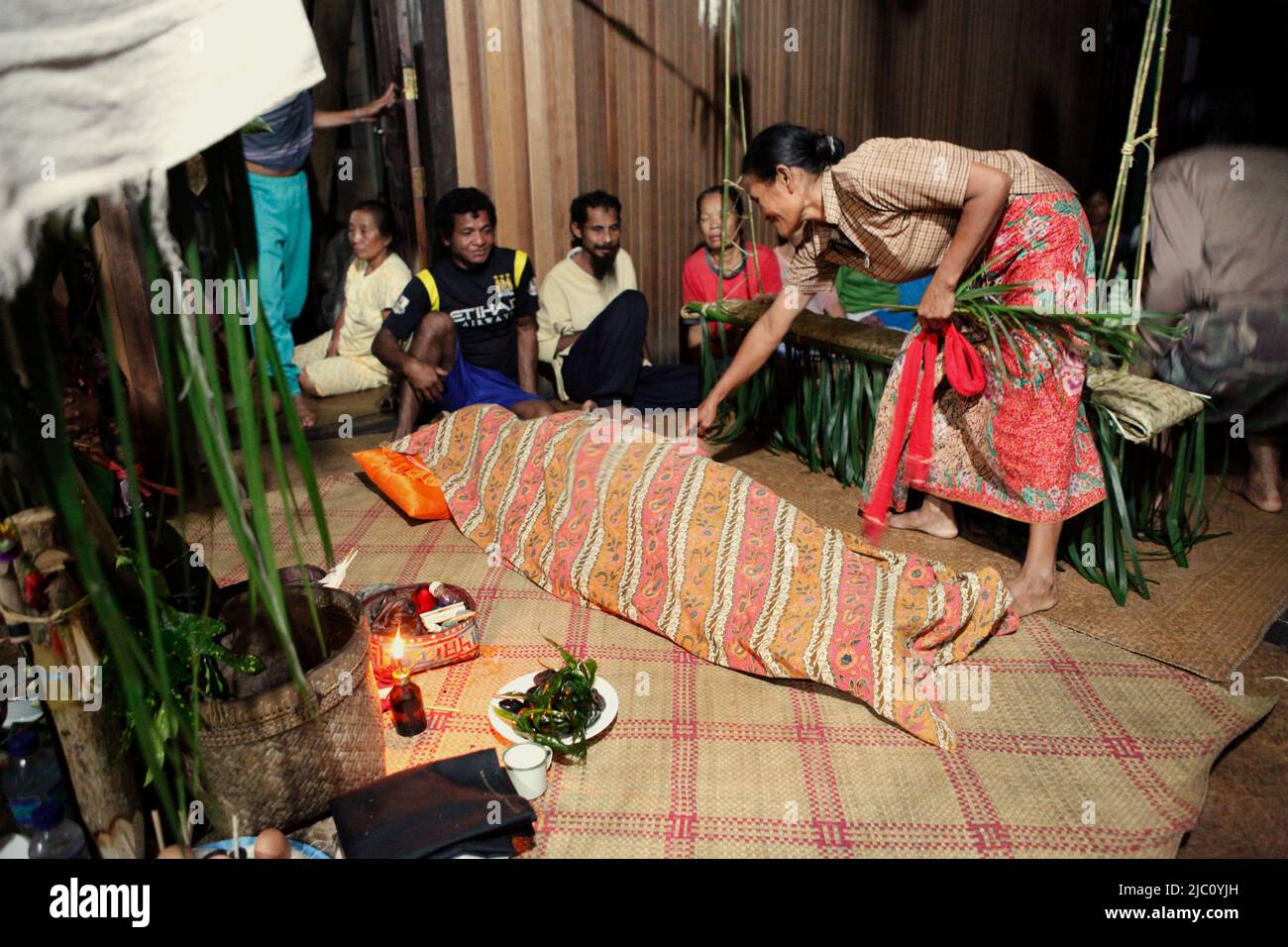 Un sorcier est recouvert d'un tissu alors qu'il est allongé sur le sol après avoir été mis en transe lors d'une pratique traditionnelle de guérison chez un patient malade (non représenté) à Sungai Utik, Batu Lintang, Embaloh Hulu, Kapuas Hulu, West Kalimantan, Indonésie. Banque D'Images