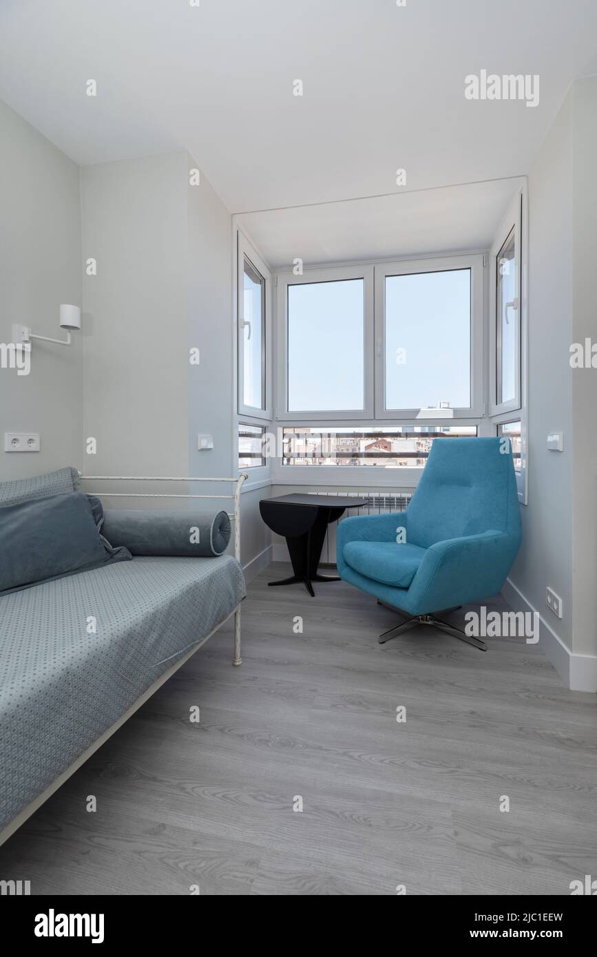 Coin d'une chambre avec un canapé-lit individuel bleu, pavillon avec vue et parquet gris Banque D'Images