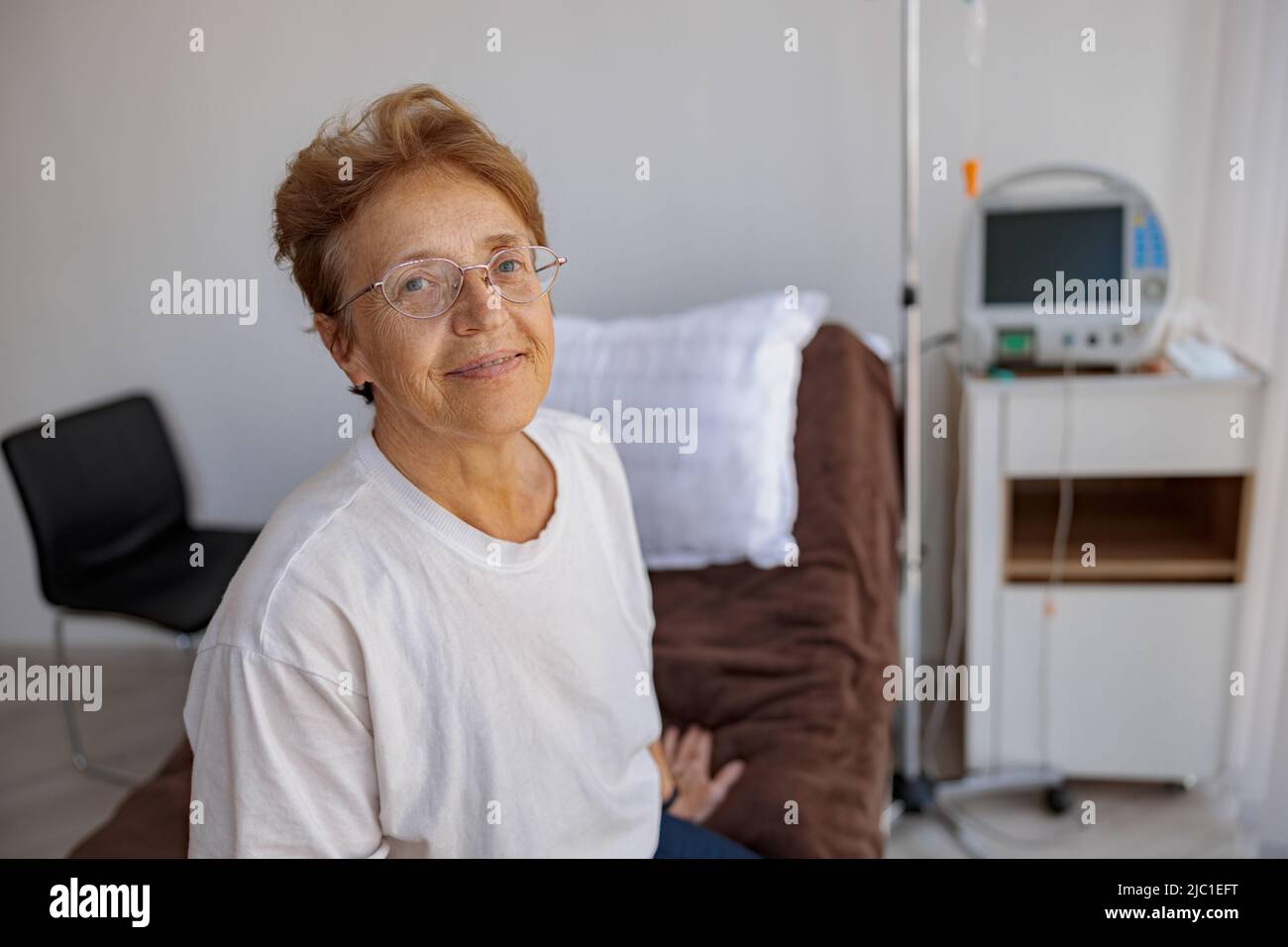 Patiente senior souriante dans la salle de la clinique médicale moderne Banque D'Images