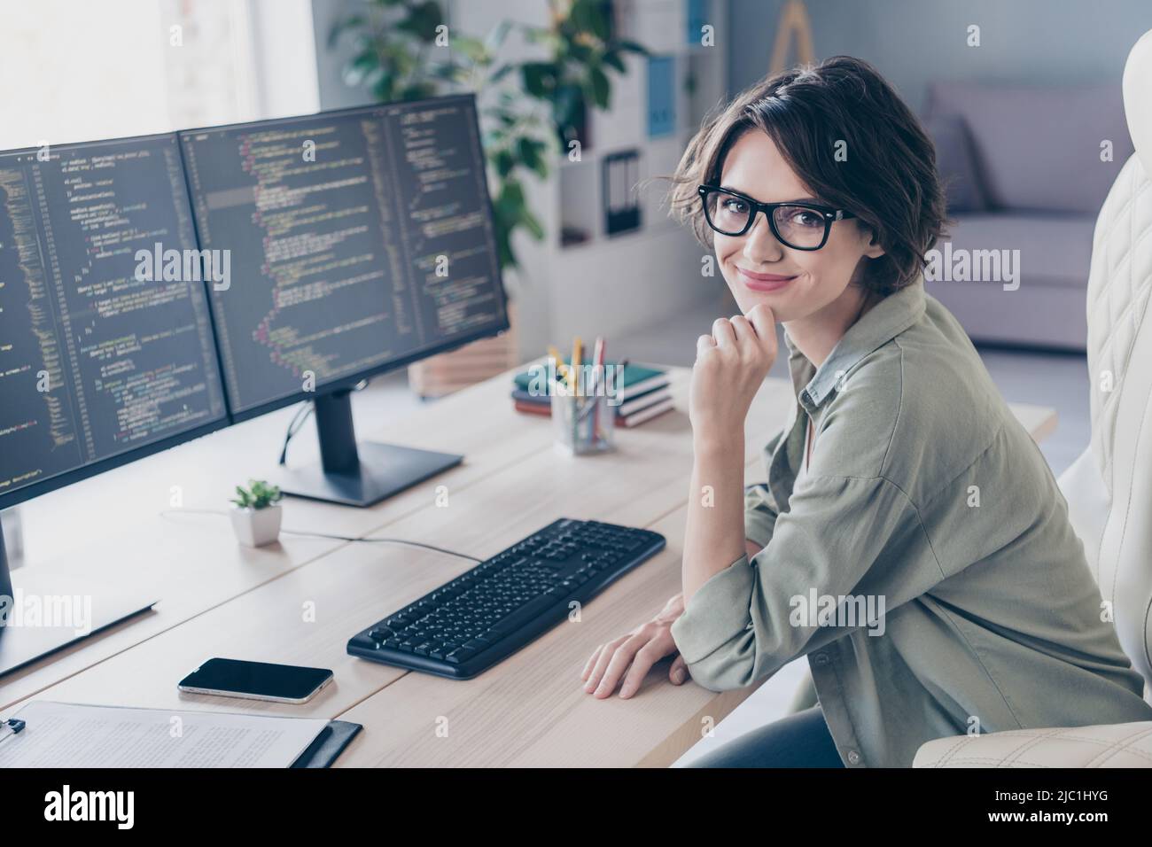 Portrait de la jolie femme chaise assise main sur le menton regarder caméra bureau bâtiment poste de travail Banque D'Images