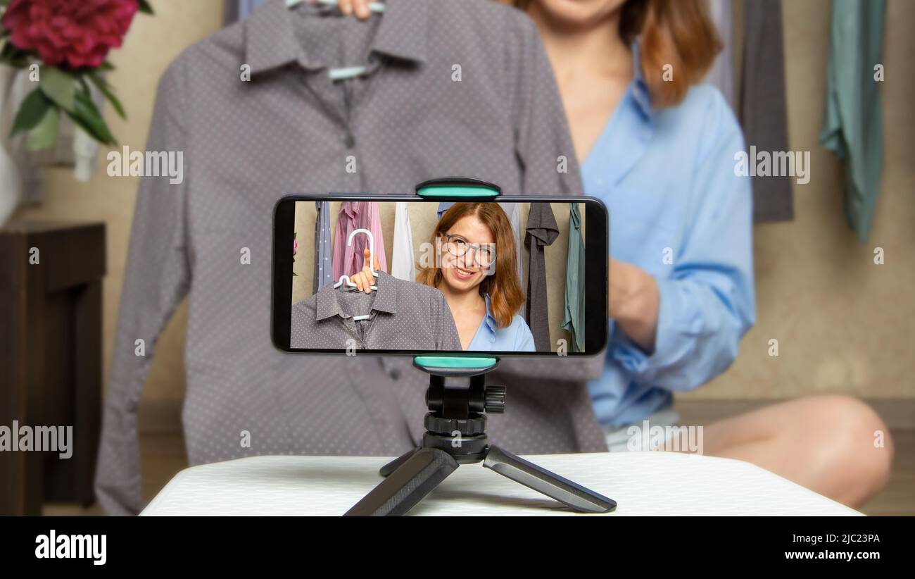 Une femme blogueuse montre des vêtements à la mode prenant des photos sur un téléphone portable. Ventes en ligne à l'aide d'un smartphone. Influenceur au travail. Banque D'Images