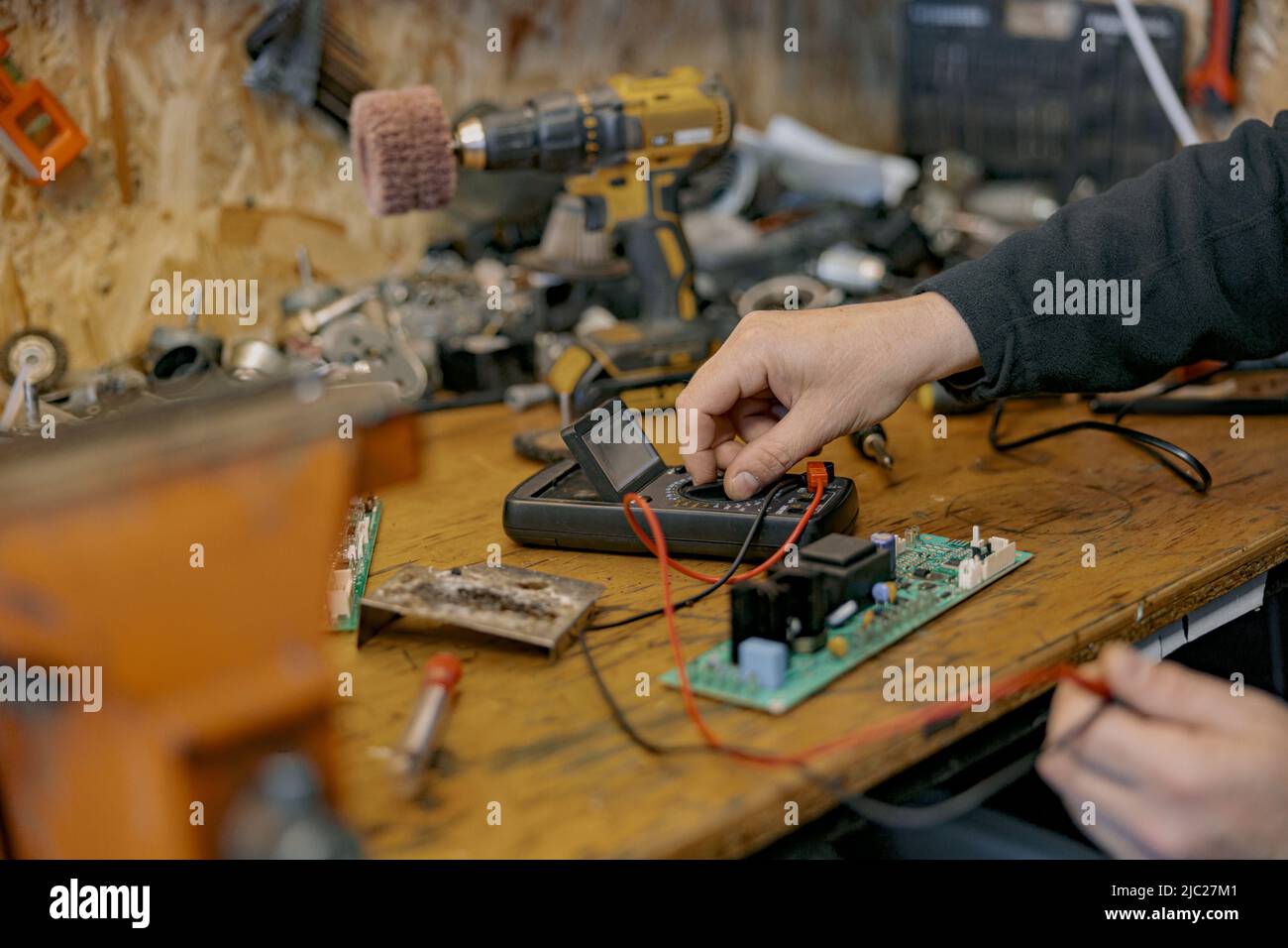 Gros plan des mains d'électricien vérifie la tension électrique sur la carte de circuit imprimé à l'aide d'un dispositif Banque D'Images