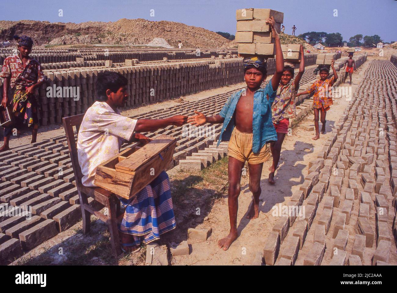 Bangladesh; enfant travailleur portant des briques. Chaque fois que le garçon transporte 6 briques, il reçoit une pièce de monnaie. Banque D'Images