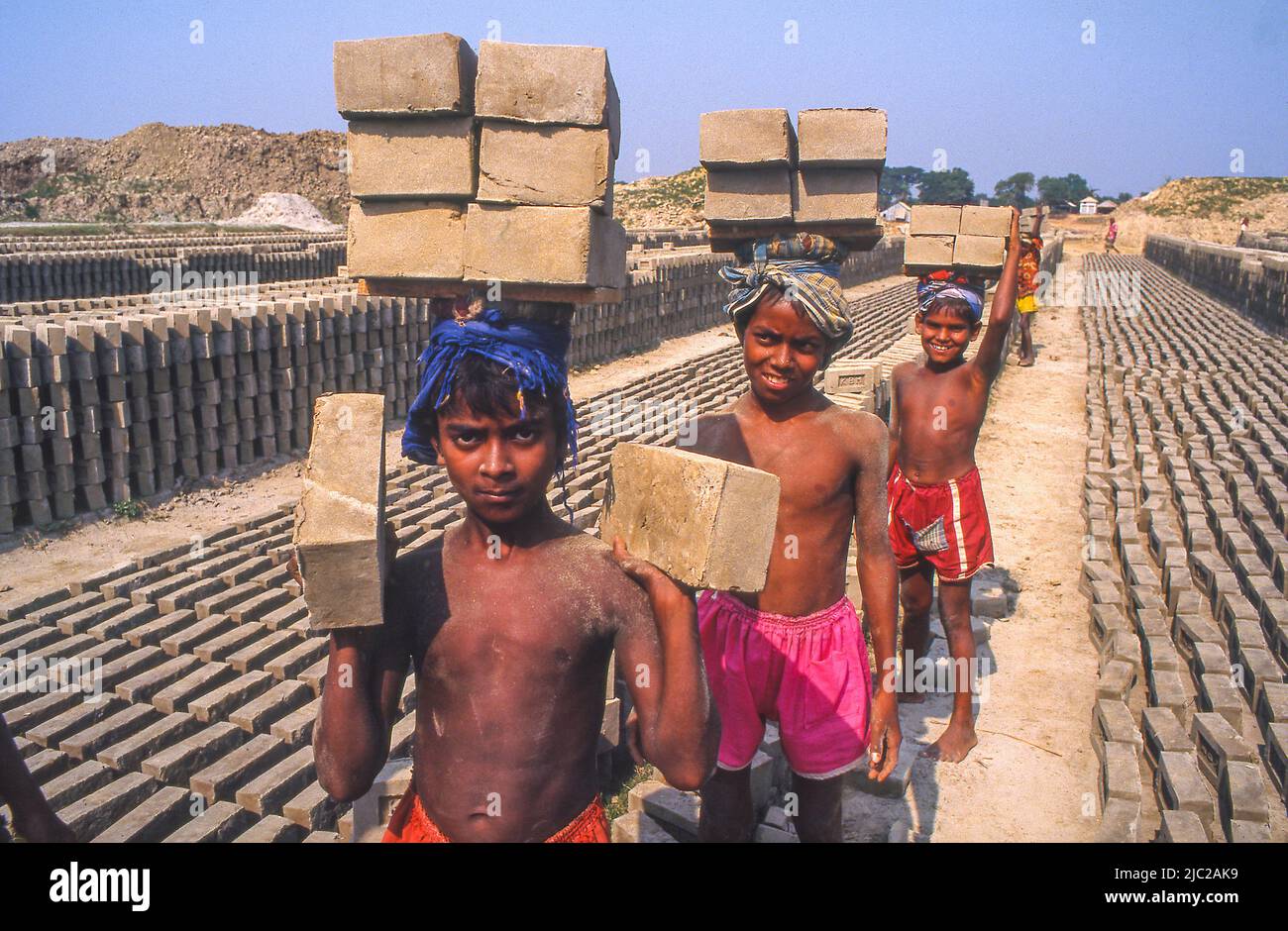 Bangladesh; enfants travailleurs portant des briques. Chaque fois qu'un garçon transporte 6 briques, il reçoit une pièce qui peut être échangée à la fin de la journée. Banque D'Images
