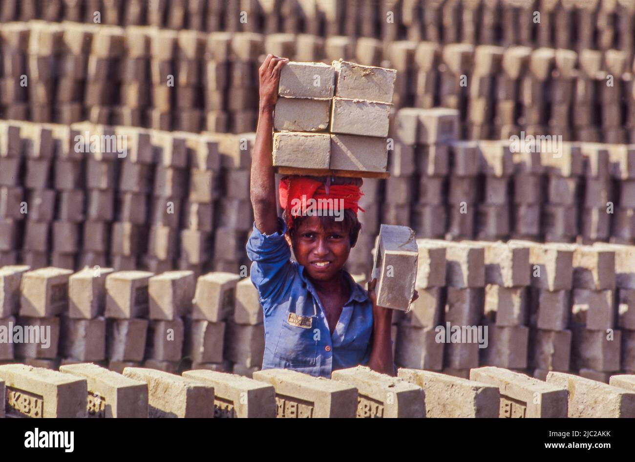 Bangladesh; enfant travailleur portant des briques. Banque D'Images