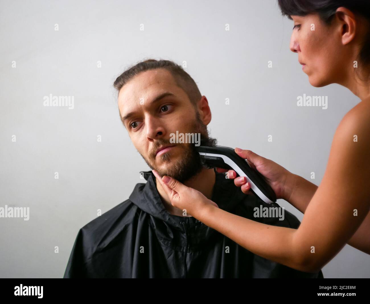 Jeune homme blanc avec barbe Obtenez une coupe de cheveux par une jeune femme Banque D'Images