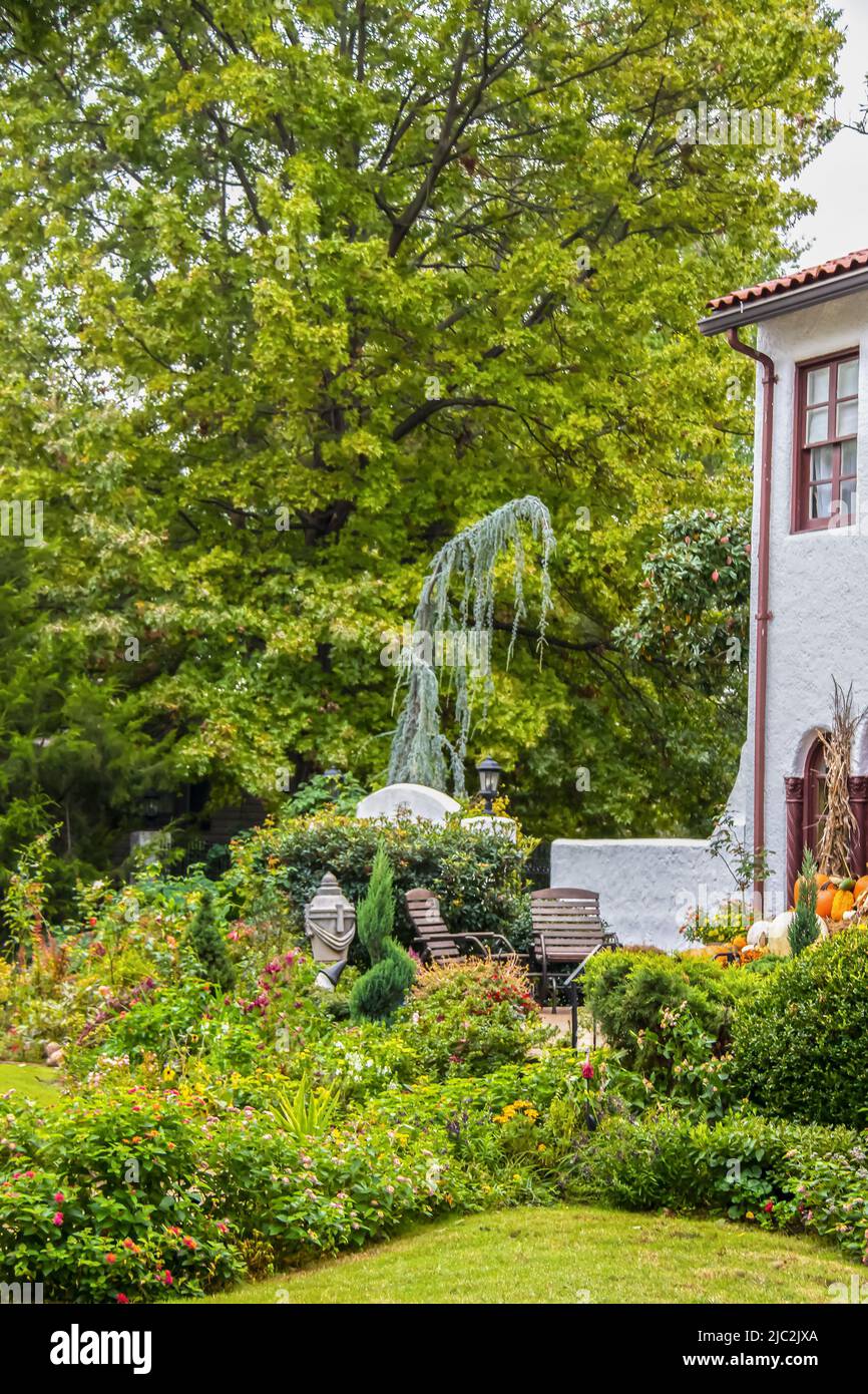 Charmant coin salon sur le patio paysagé à l'extérieur de la maison en stuc de deux étages avec décor lointain et citrouille - arbres flous en arrière-plan Banque D'Images