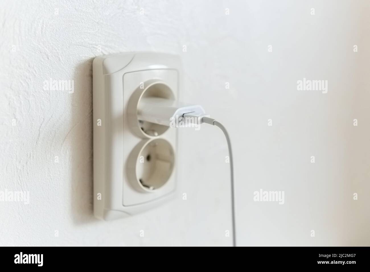 Gros plan d'un chargeur de smartphone connecté à une prise euro. Banque D'Images