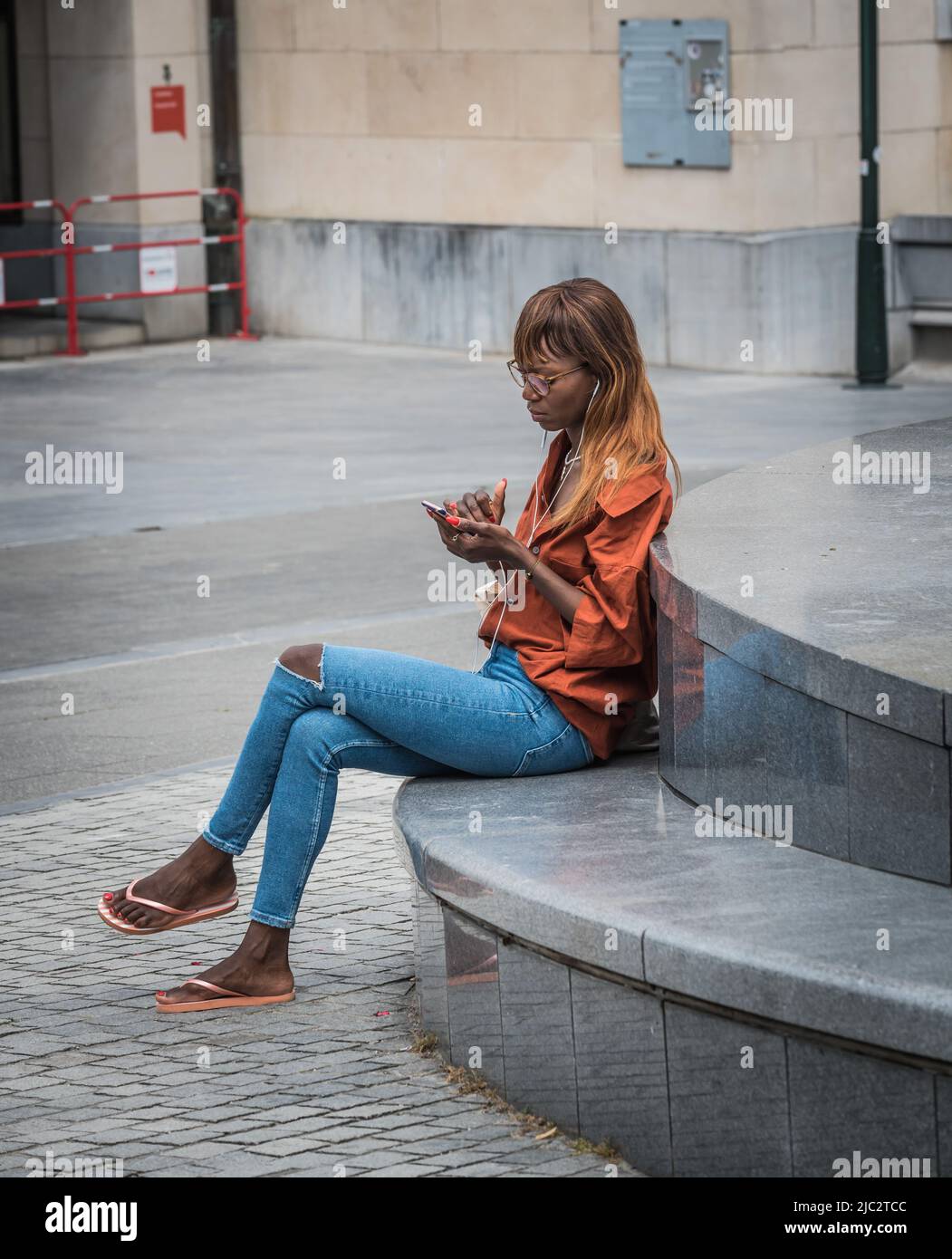 Centre ville de Bruxelles, région de la capitale de Bruxelles - Belgique - 06 20 2020 jeune femme à la mode avec des cheveux teints vérifiant son téléphone au Mont des Arts Banque D'Images