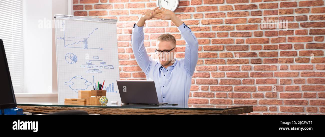 Close-up of a Happy Businessman Relaxing On Fitness Ball in Office Banque D'Images