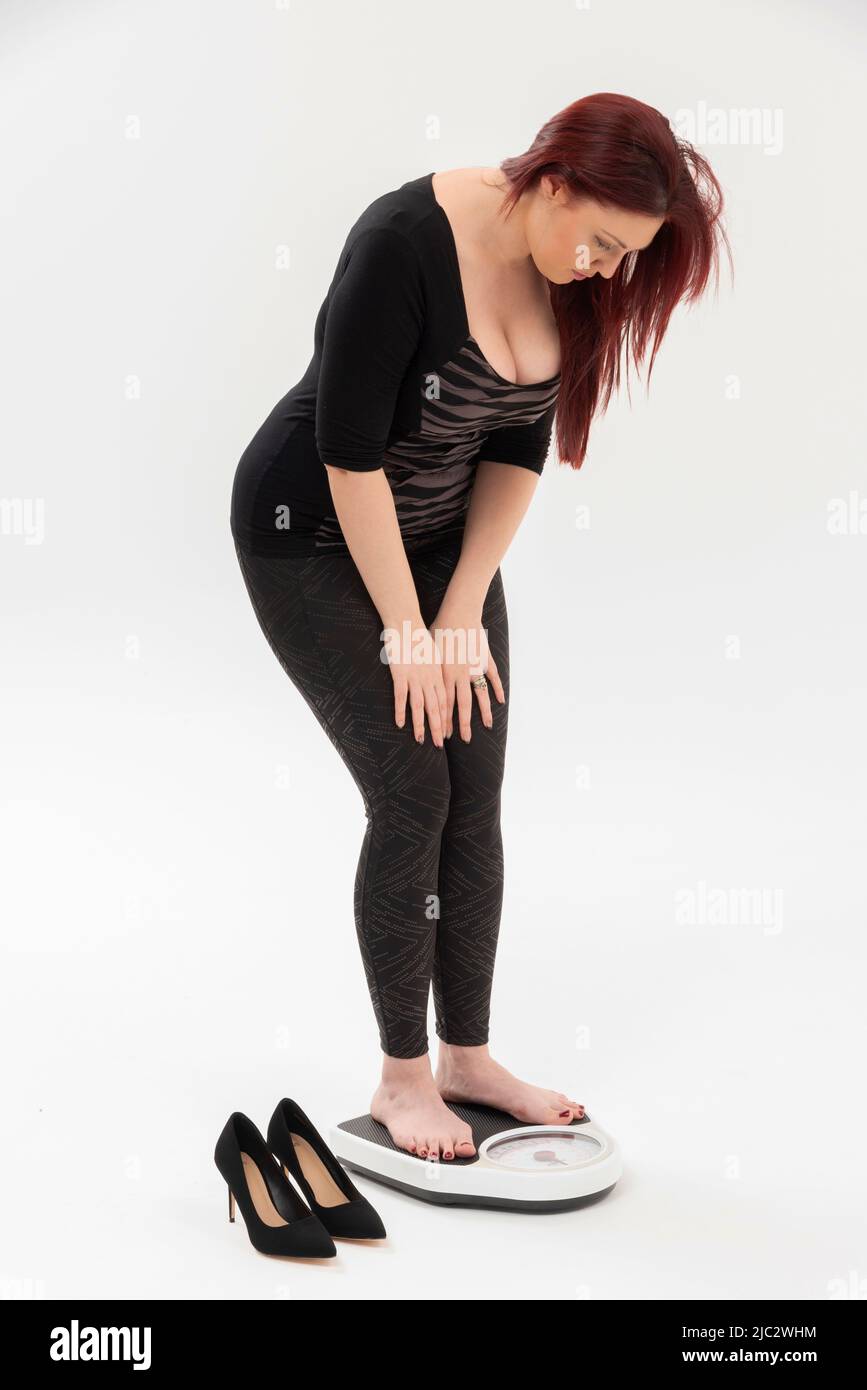 Wiltshire, Angleterre, Royaume-Uni. 2022. Femme utilisant un ensemble de pèse-personne pour vérifier son poids. Banque D'Images