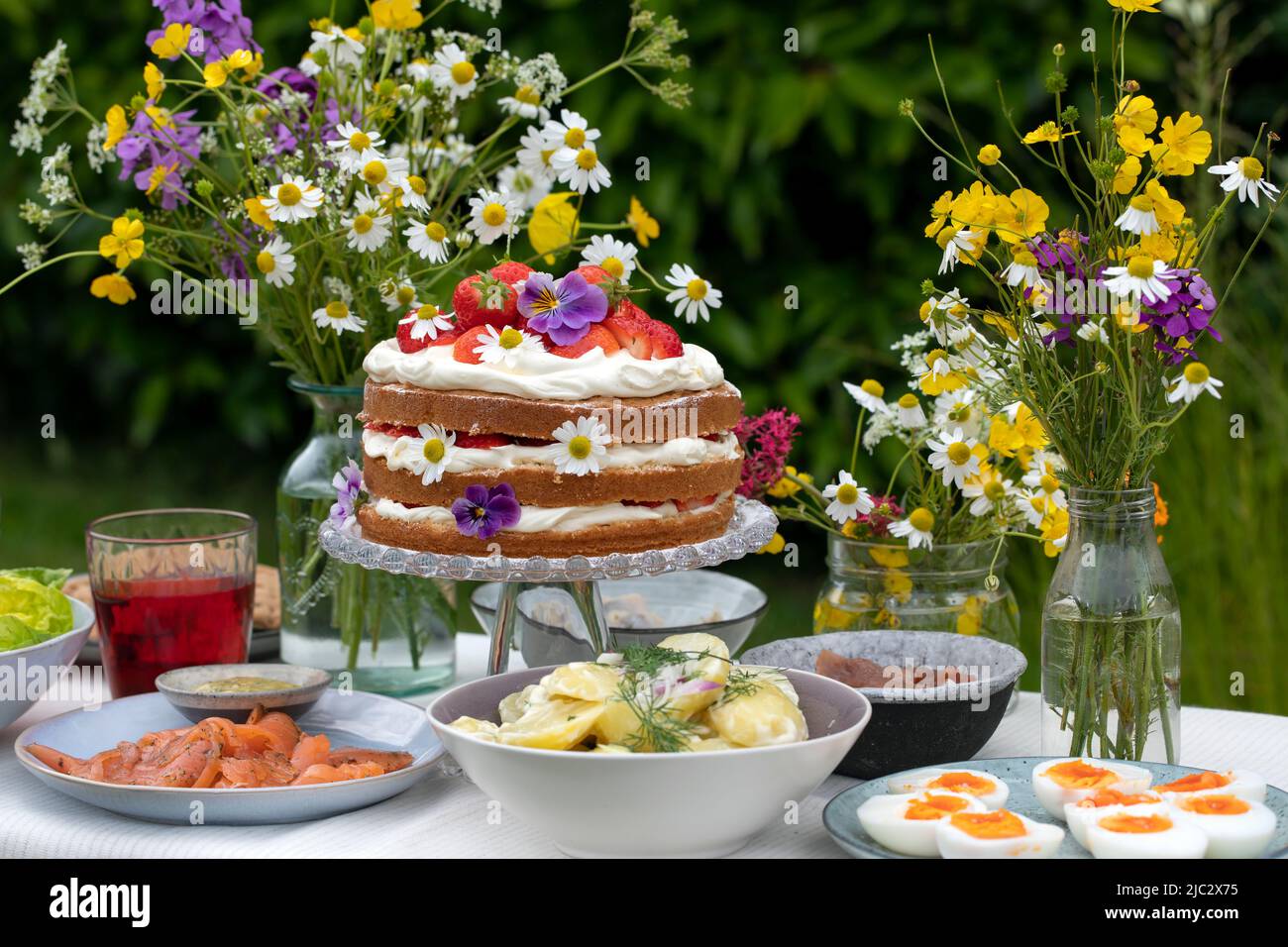 Repas scandinave mi-été avec gâteau à la fraise et à la crème, salade de pommes de terre, saumon et œufs Banque D'Images