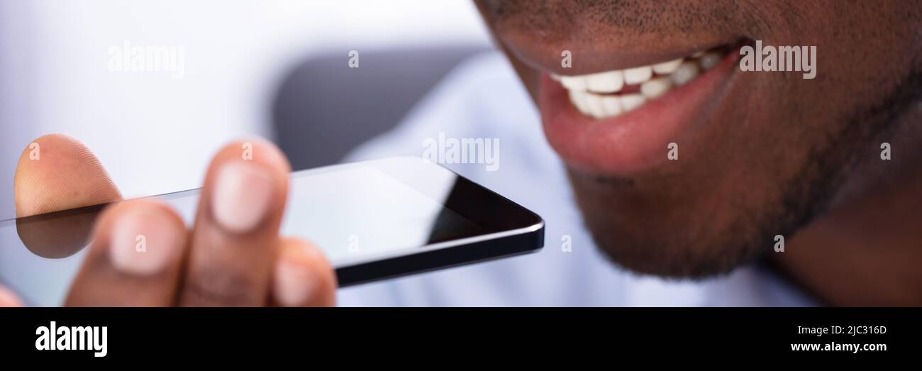 Gros plan d'un homme africain en utilisant l'assistant vocal On Cellphone Banque D'Images