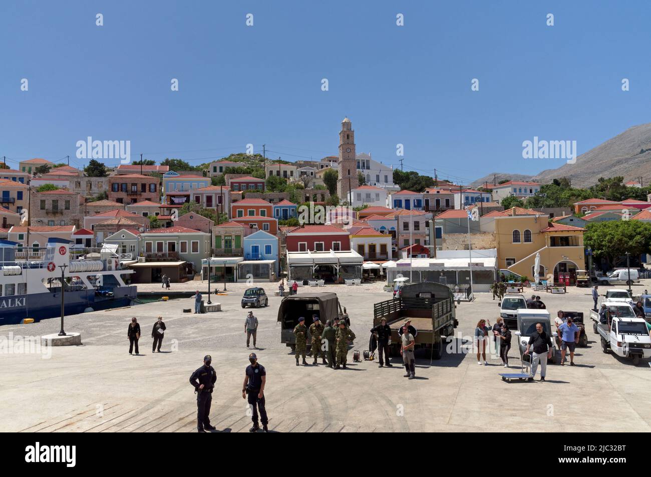 Vue depuis le ferry Dodécanèse Express jusqu'à l'île de Halki, près de Rhodes. Soldats et touristes sur le port. Banque D'Images