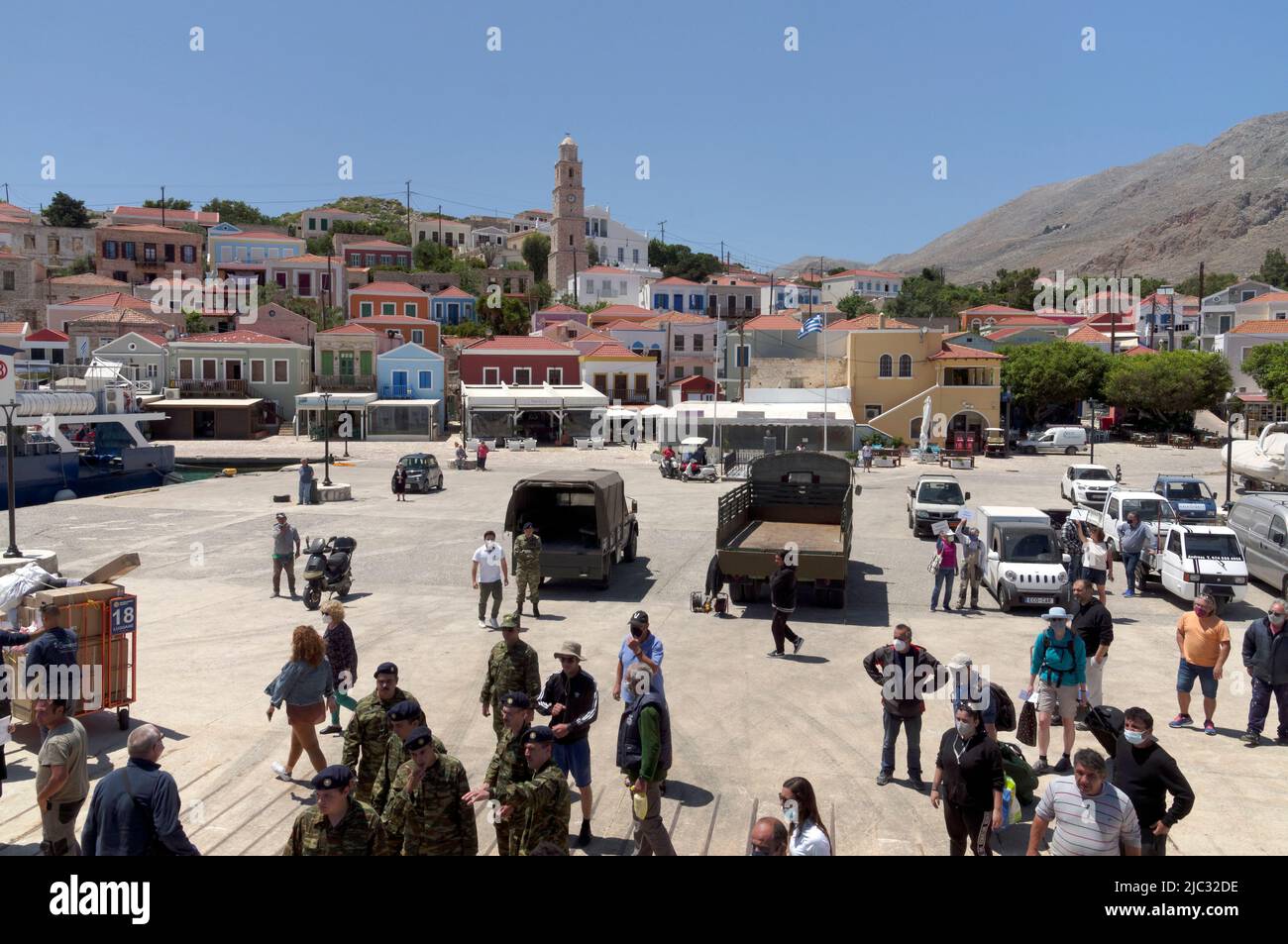 Vue depuis le ferry Dodécanèse Express jusqu'à l'île de Halki, près de Rhodes. Soldats et touristes sur le port. Banque D'Images