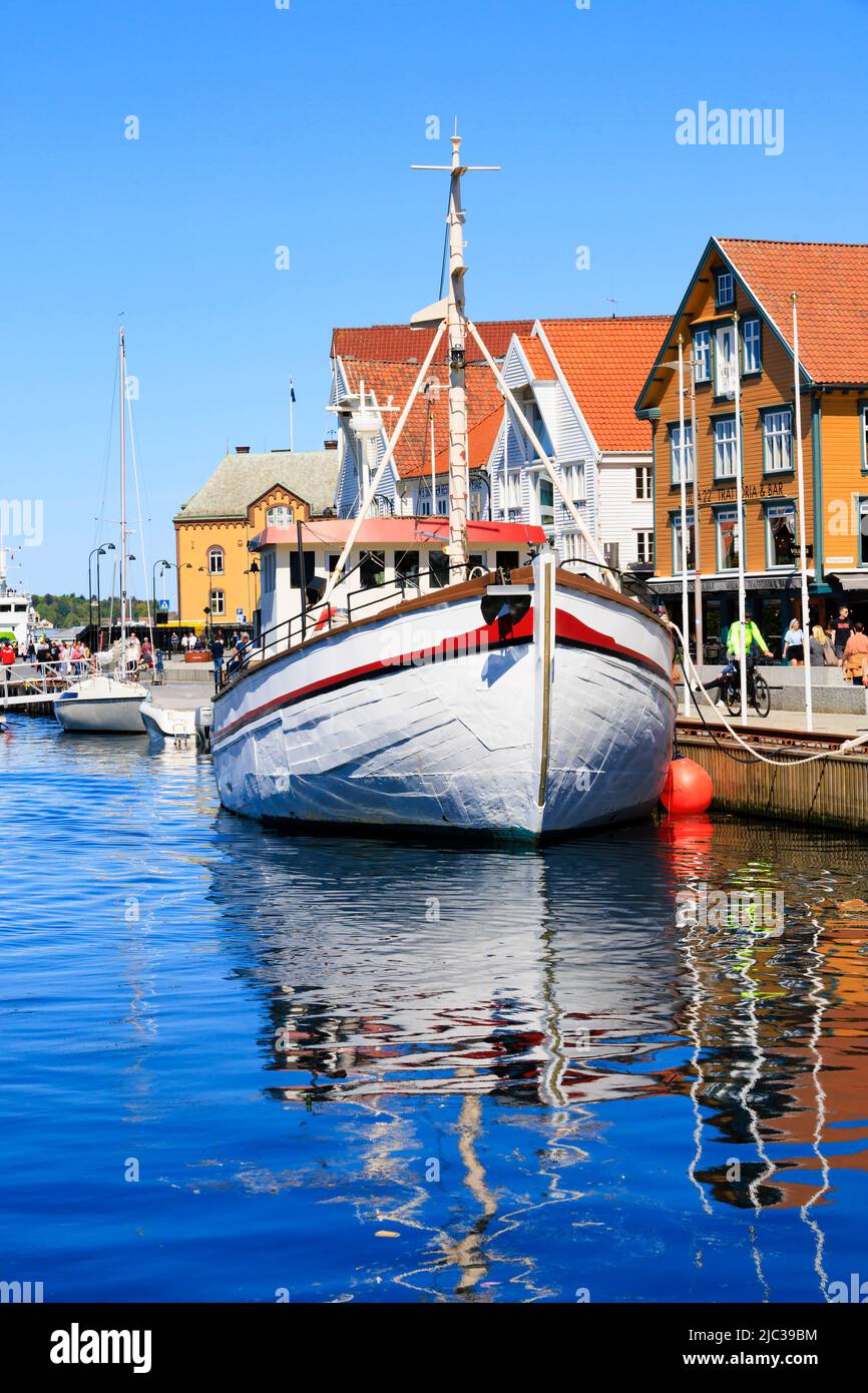 Bateau de pêche norvégien traditionnel amarré dans le port de Stavanger. Les anciens entrepôts du quai sont maintenant des restaurants, des bars et des cafés branchés., Norvège Banque D'Images