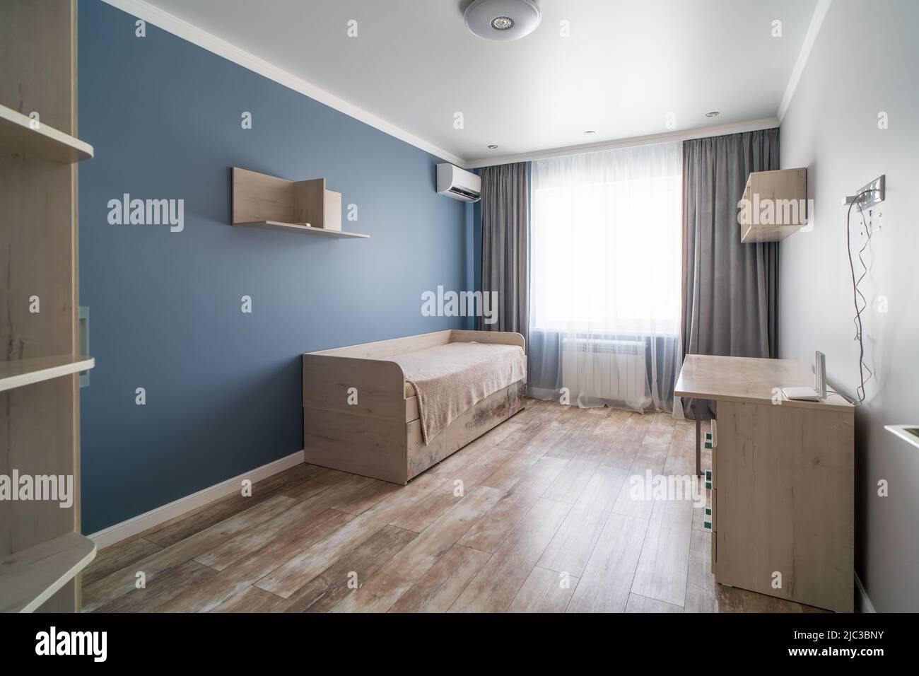 Chambre moderne pour enfants aux couleurs pastel discrètes avec lit et table de travail. Banque D'Images