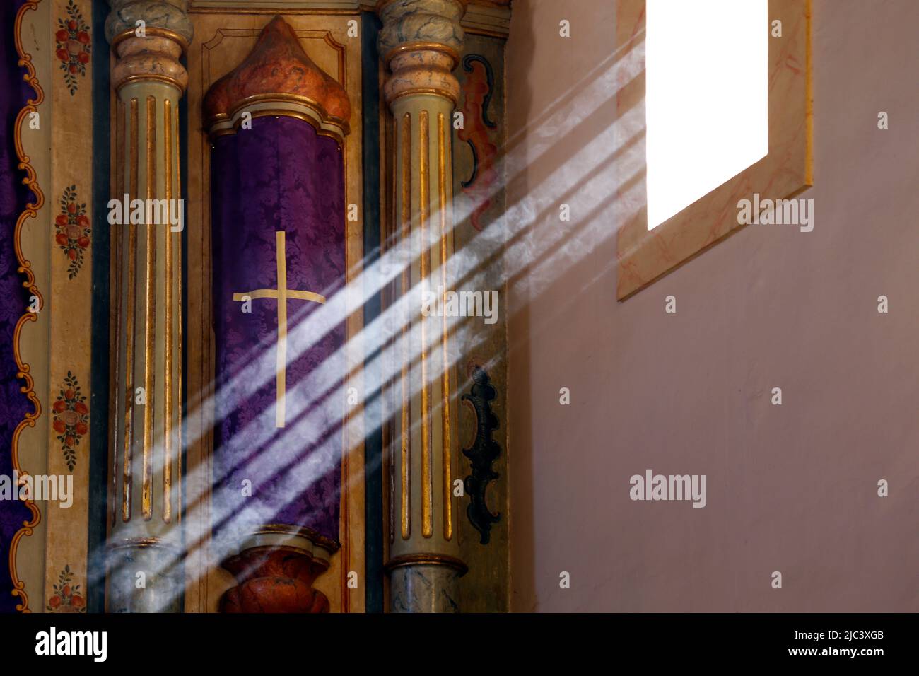 Symbole religieux avec tissu de couleur pourpre et motif de la croix recevant les rayons du soleil de la lumière de fenêtre Banque D'Images