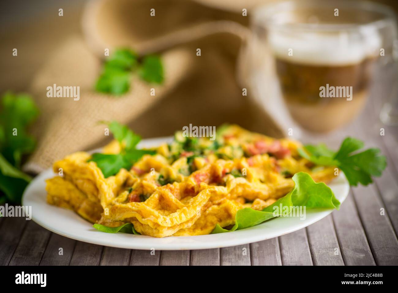 Omelette aux œufs farcie avec des légumes verts et des saucisses frits sous forme de gaufres, sur une table en bois Banque D'Images
