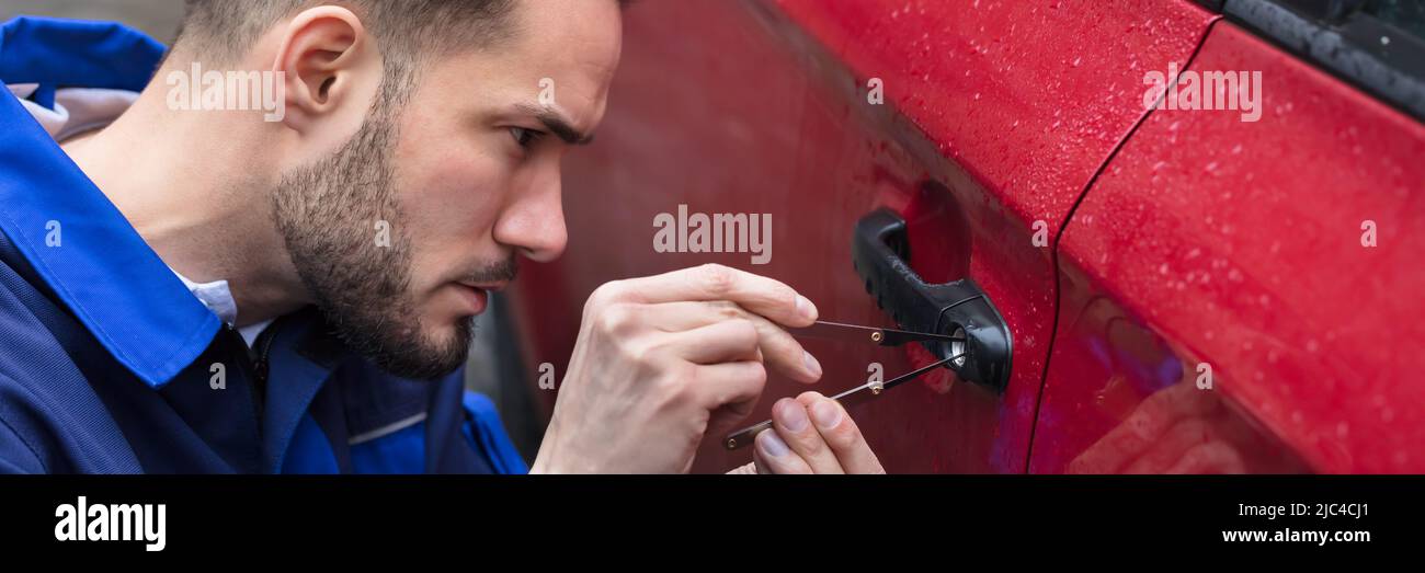 Jeune homme rouge d'ouverture de porte de voiture avec Lockpicker Banque D'Images