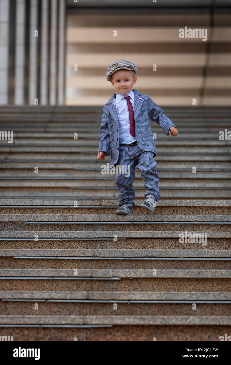 Portrait d'un petit garçon sur les marches à l'extérieur. Prise de vue pour enfants. Concept de mode de vie des enfants Banque D'Images