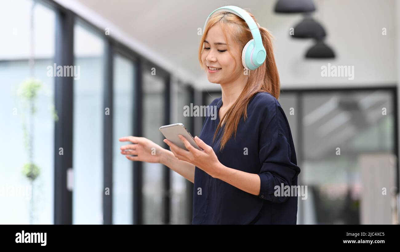 Joyeuse femme asiatique portant un casque Profitez de votre chanson préférée tout en passant du temps libre à la maison. Ambiance, passe-temps, concept moderne de technologie sans fil Banque D'Images