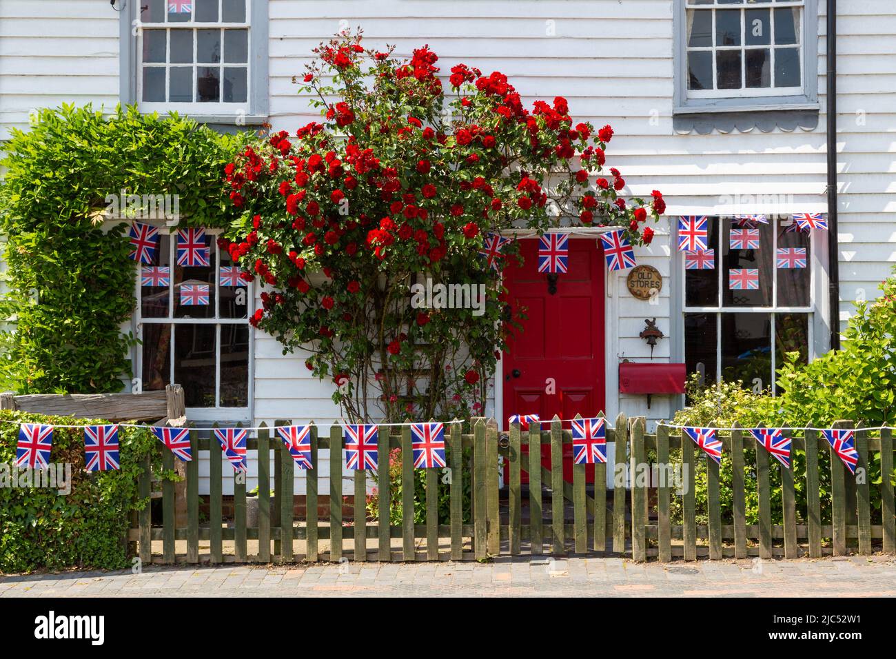 Village cottage avec roses rouges, panneaux de planches à voile, british Union Jack bunting décoré pour le jubilé de platine queens, Hamstreet, kent, royaume-uni Banque D'Images