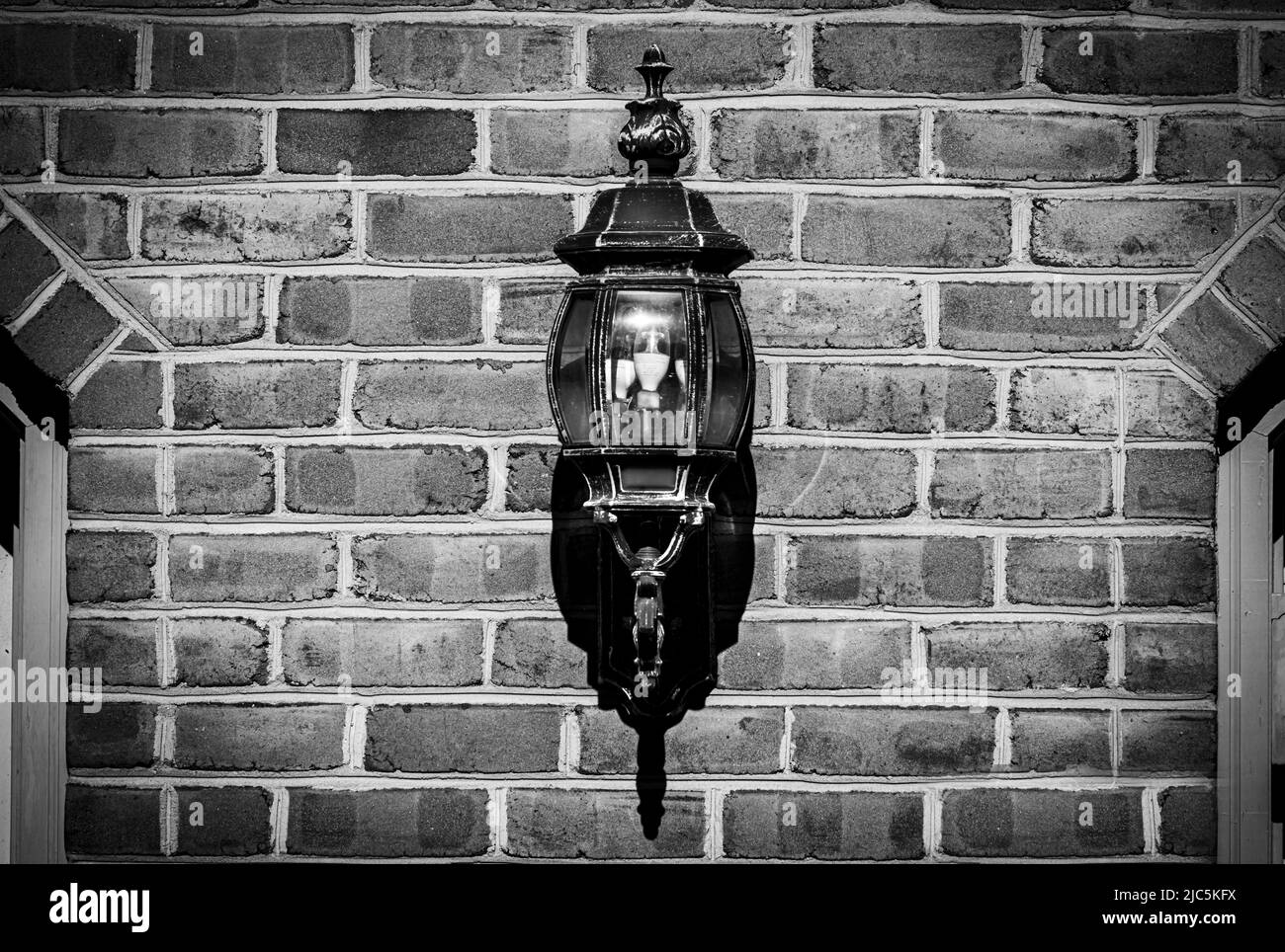 Une lampe de garage accrochée sur un mur de briques entre deux portes de garage, hiver, printemps, été, automne, Lancaster, Pennsylvanie Banque D'Images
